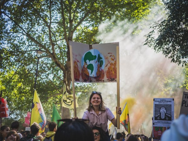 Girl riding someone's shoulders during climate protest.