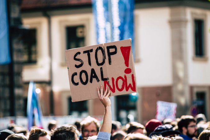 Poster at protest reading "stop coal now."