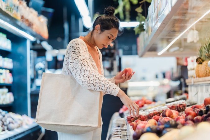 Woman shopping for fruit in grocery store.