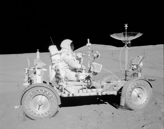 Apollo 15 astronaut on lunar rover in black and white NASA image