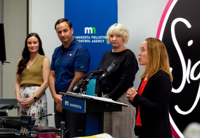 MPCA commissioner Katrina Kessler speaking into a microphone as three other people look on. 