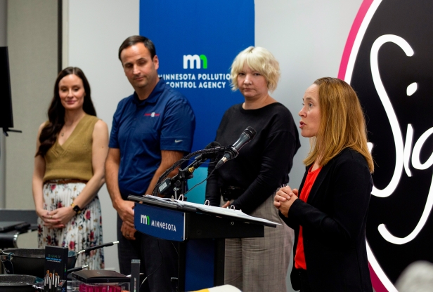 MPCA commissioner Katrina Kessler speaking into a microphone as three other people look on. 