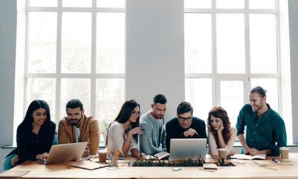 group of women and men huddled around two laptops