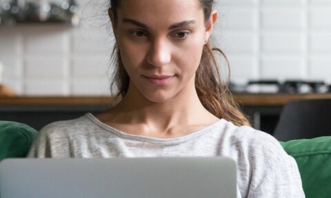 women sitting on green couch working on laptop