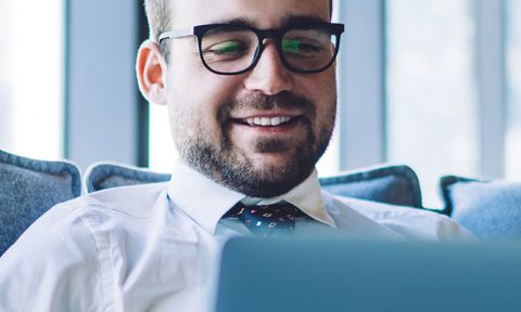 man on laptop while sitting on comfy chair