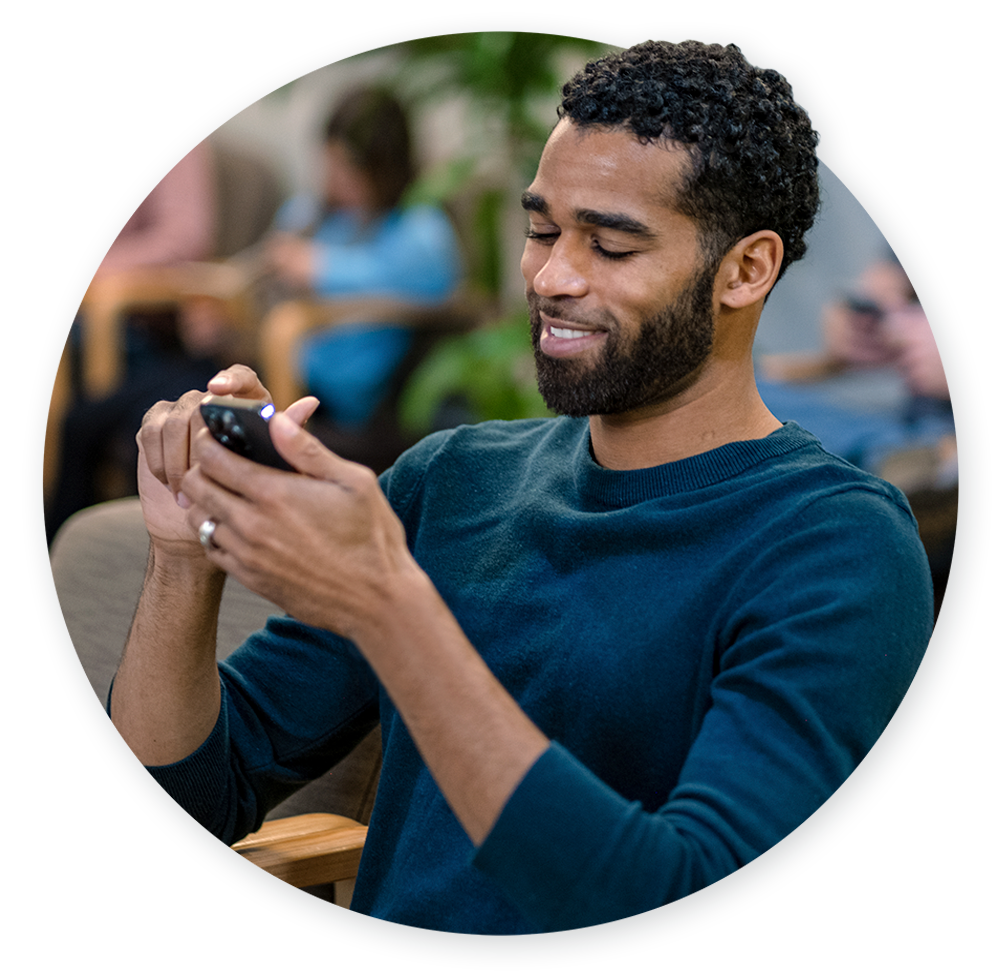 Male patient in waiting room scrolling on mobile phone