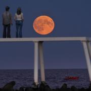 The full harvest moon rises over The Couple sculpture at Newbiggin-by-the-Sea in Northumberland (Owen Humphreys/PA)