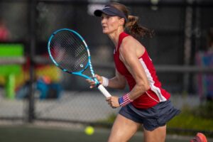 An action shot of a woman holding a tennis racket and waiting for a ball.