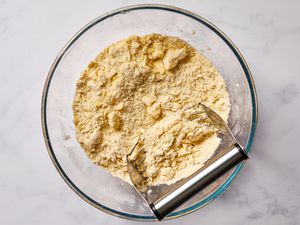 pastry cutter in a bowl with flour and pieces of butter