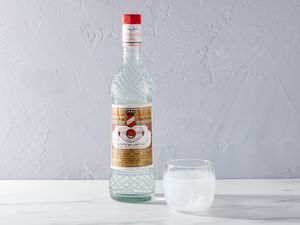 A bottle of Arak liquor with a glass of Arak and water mix, over ice