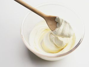 Using wooden spoon to stir frosting in glass bowl