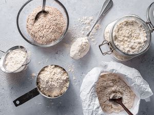 a variety of wheat flours in bowls, measuring cups and bags