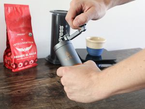 A person grinding coffee beans using the VSSL Java G25 Coffee Grinder