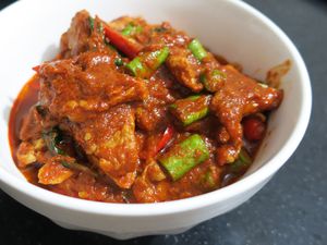 White Bowl filled with red curry that includes beef and vegetables such as green beans