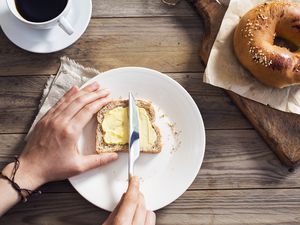 Woman's hand spreading margarine on sliced bread