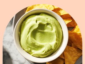 Super smooth guacamole in a white ramekin with tortilla chips on the side