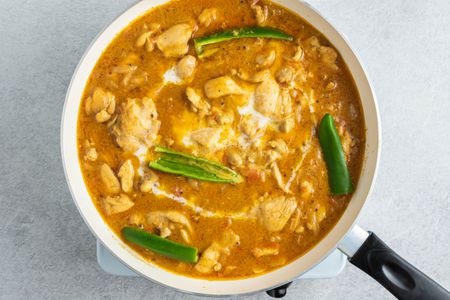 South Indian-Style Chicken Curry with green chiles in a pan 