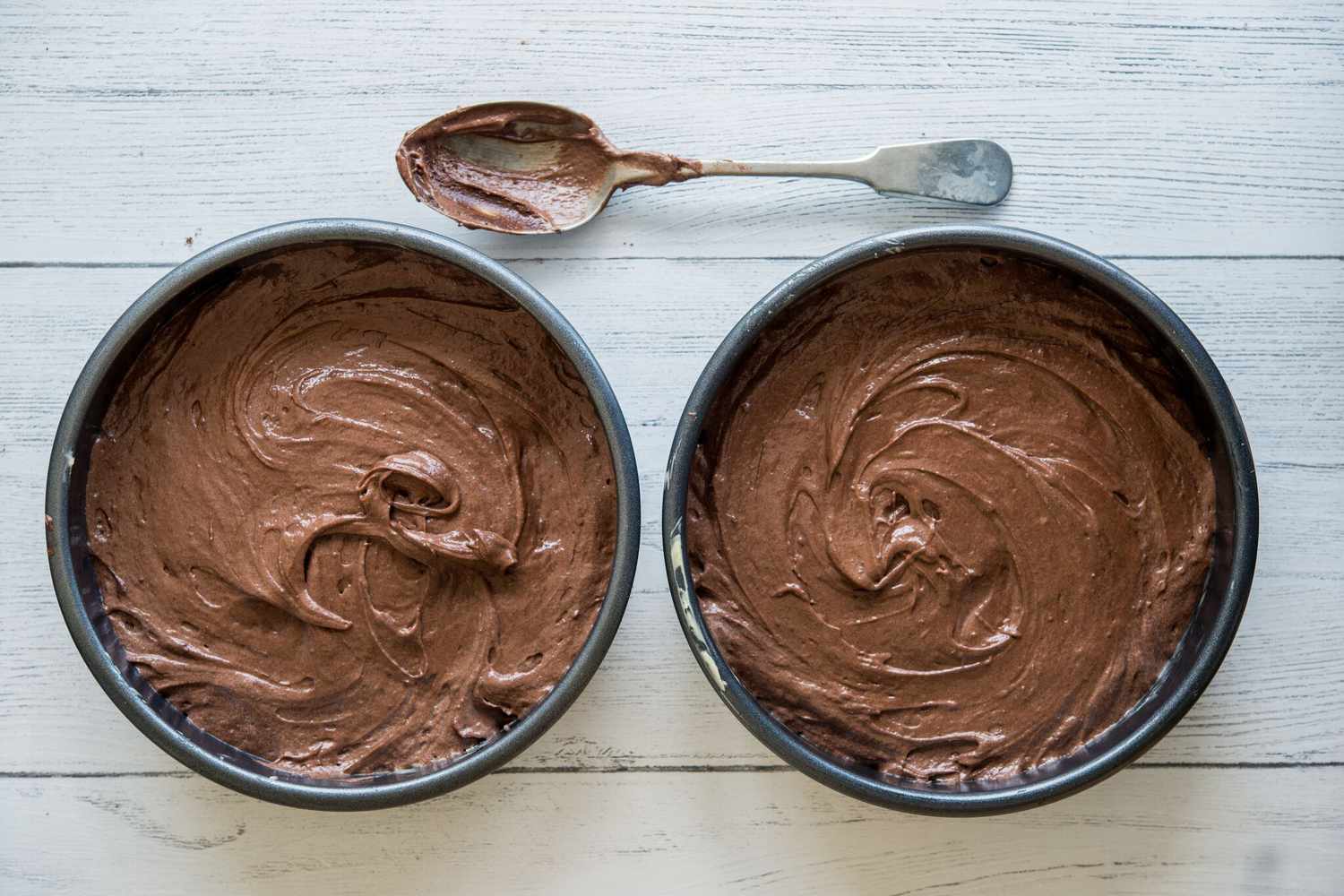 Adding batter to pans for chocolate cake