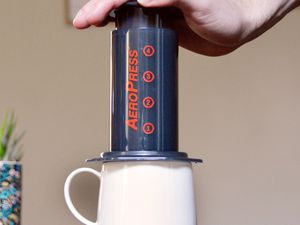 Hand pushing down on the AeroPress coffee maker