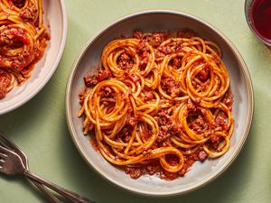 Two bowls of spaghetti bolognese served with red wine