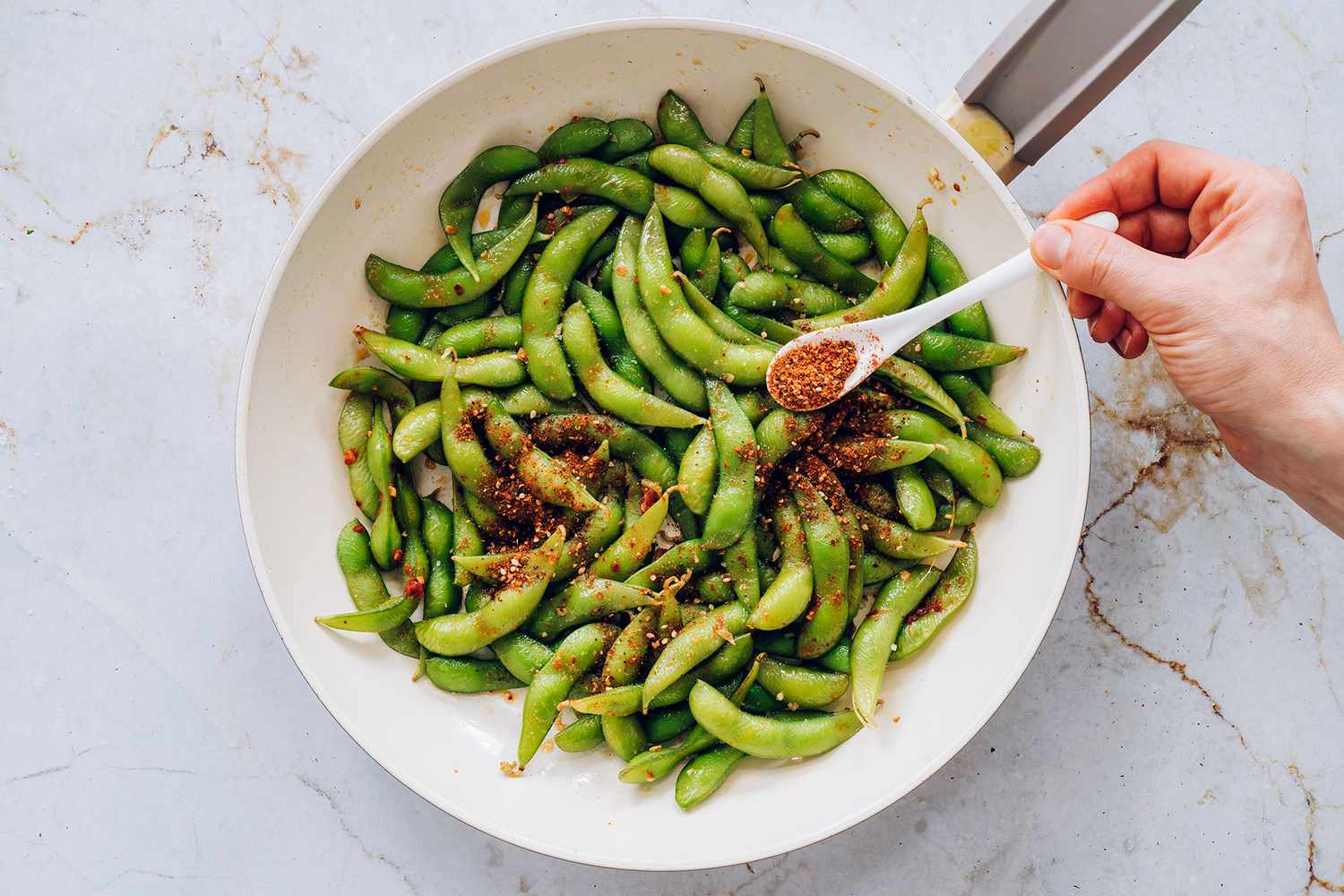 Add shichimi togarashi to the edamame mixture in the pan