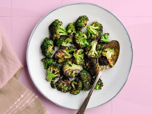 A plate of browned roasted broccoli with a serving spoon