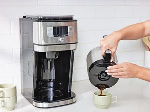 Person pouring coffee into a green cup from the Cuisinart Burr Grind & Brew Coffee Maker with Thermal Carafe