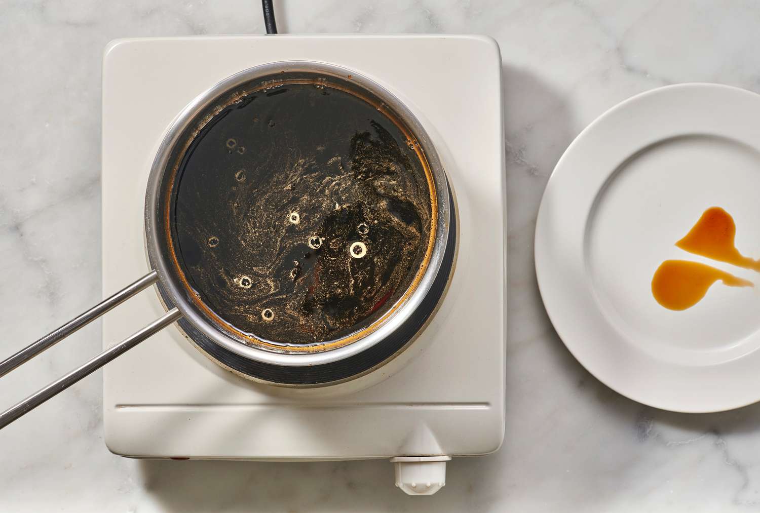 A pot of simmering soy-mixture, and a plate with a small amount of sauce on it