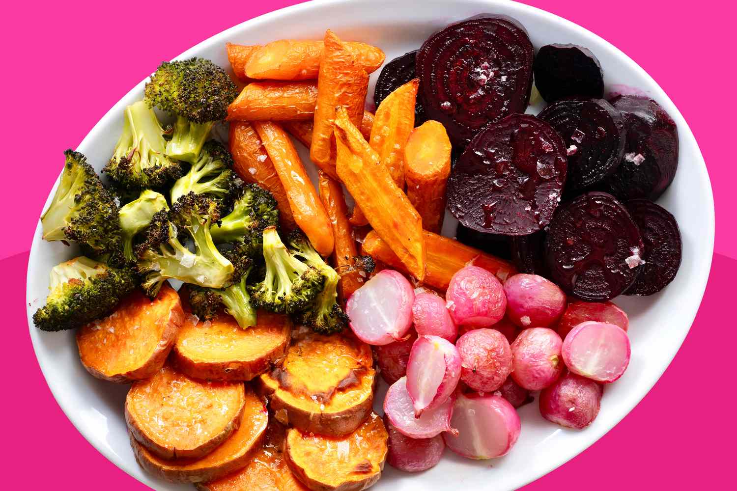 A platter loaded with roasted vegetables: broccoli, carrots, halved radishes, sweet potato rounds, and beet rounds