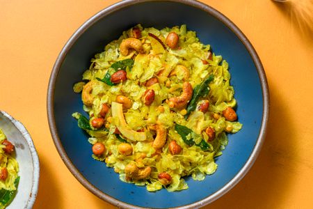 A blue bowl of poha chivda, with a smaller bowl in the corner of the frame