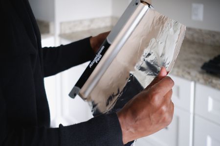 person removing aluminum foil from roll