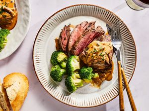 A plate of sliced Steak Diane served with broccoli and bread