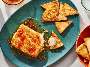 A platter with fried feta with sesame seeds and honey, served with pita chips