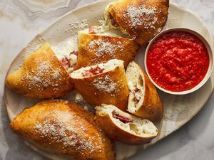 calzones on platter with tomato sauce in bowl