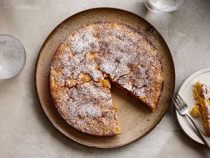 A French apple cake on a large serving plate with a slice removed, and a small plated slice