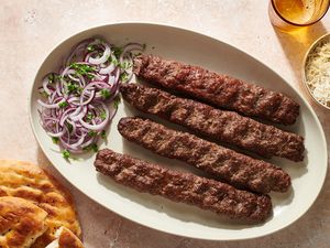 Kabob Koobideh (Persian Grilled Kebabs) on a platter with an onion salad 