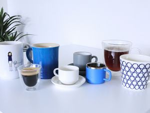 A variety of coffee mugs and espresso cups on a white surface