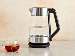 OXO Brew Cordless Glass Electric Kettle on a counter next to a glass cup with tea