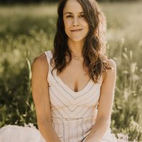 Woman in a white dress with stripes sitting in the grass