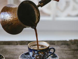 A woman is pouring Turkish Coffee in a coffee cup