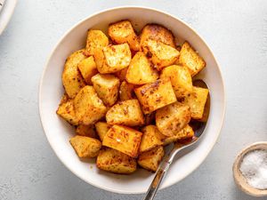 A bowl of roasted potatoes with paprika, served with extra salt on the side