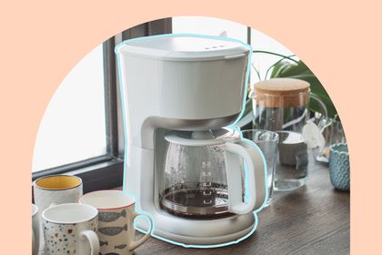 A drip coffee maker on a countertop surrounded by coffee mugs