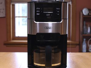 Gevi 10-Cup Grind and Brew Automatic Drip Coffee Maker displayed on a counter in front of a window