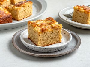 A slice of apple snacking cake with a platter of apple snacking cake