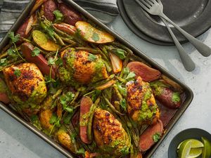 A sheet pan of Thai curry chicken thighs, served with lime wedges