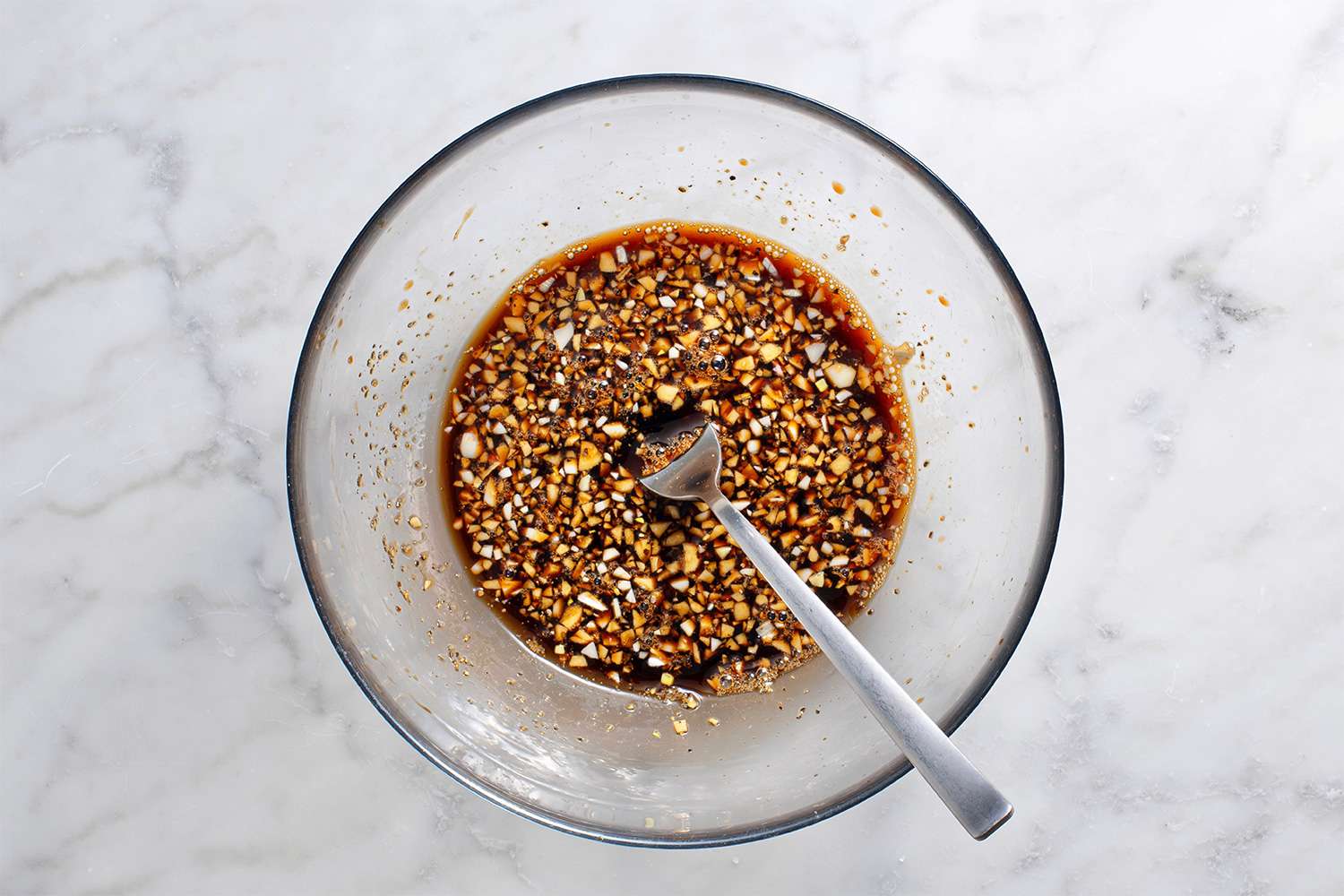 Soy sauce, half of the garlic, lemon juice, brown sugar, and black pepper in a bowl with a fork