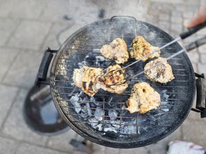 Meat on barbecue with smoking coals and hands with tongs lifting meat