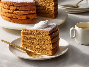 A slice of Appalachian apple stack cake, topped with whipped cream and served with a mug of coffee