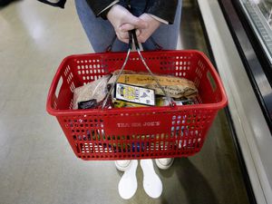 person holding shopping basket at Trader Joe's