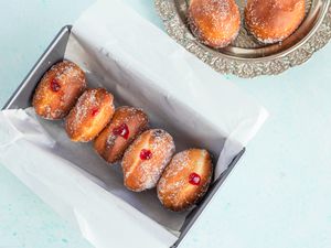 Polish pączki doughnuts recipe in waxed paper in a pan